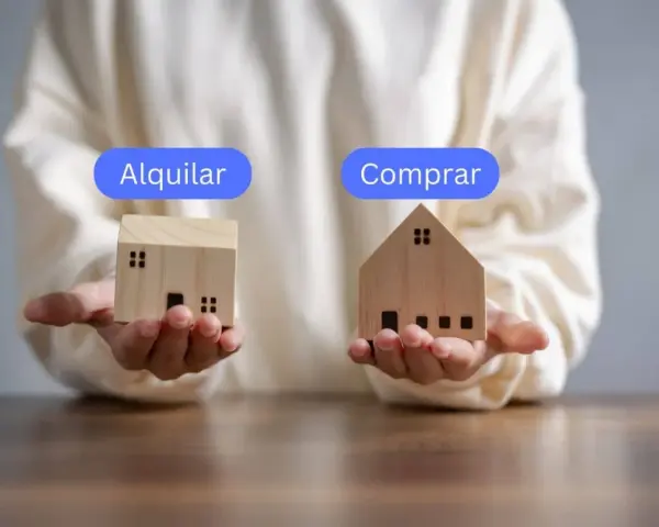 Manos sostienen casas de madera, una con "Alquilar" y otra con "Comprar", planteando la duda de si vivir de alquiler toda la vida es la mejor opción.