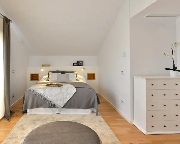 Habitación hermanos poco espacio, con cama doble, alfombra y cómoda blanca.