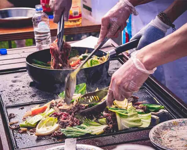 Cocina al aire libre, carne y verduras en plancha. Cumpliendo la normativa barbacoas Catalunya para disfrutar de la comida.