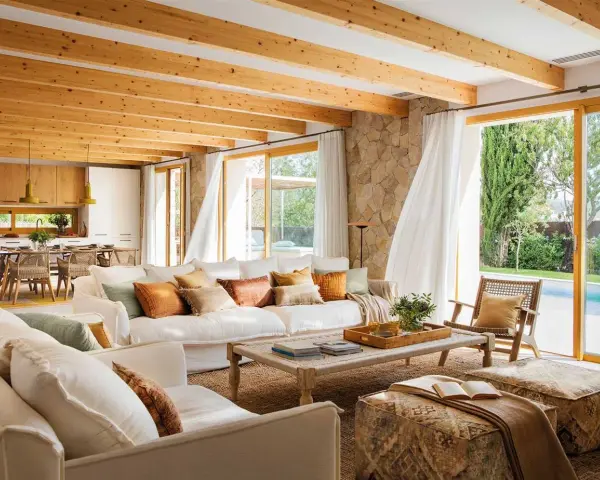 Salones blancos y madera con vigas expuestas, sofás cómodos y vistas a una piscina.