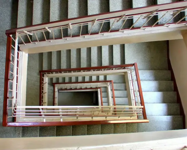 Vista cenital de un **rellano edificio** con escaleras en espiral, barandillas de metal y hormigón.