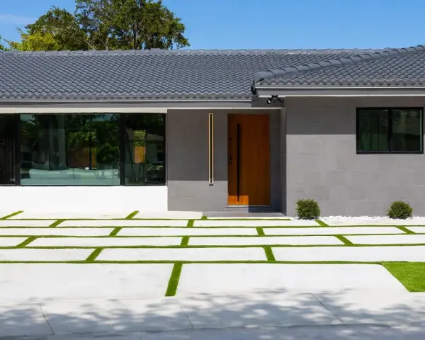Casa moderna con entrada de madera y ventanal. El camino de acceso combina cemento y césped, ideal si me separo y quiero quedarme el piso.