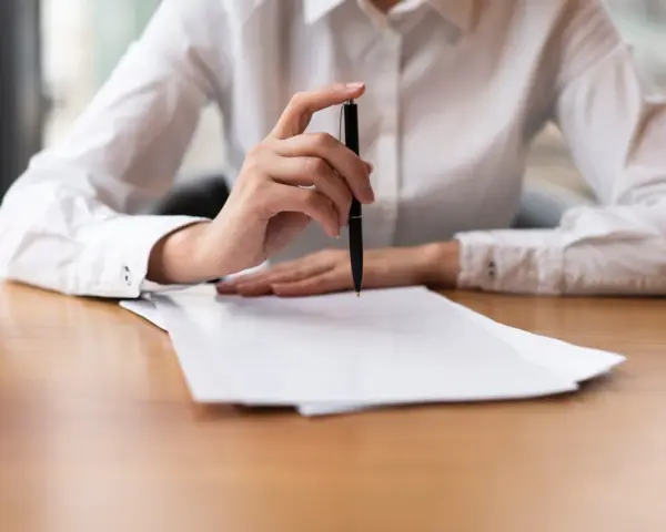 Mano con bolígrafo sobre papeles, revisando documentos. Quizás para resolver el lío de que he heredado una casa sin escrituras.