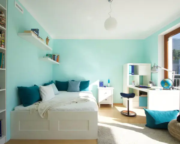 Habitación con pared verde menta y gris, cama blanca, estanterías y escritorio.