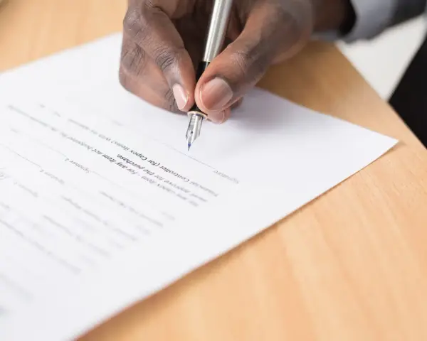 Mano firmando un documento legal. Se puede escriturar una casa a nombre de otra persona mediante este tipo de acuerdos.