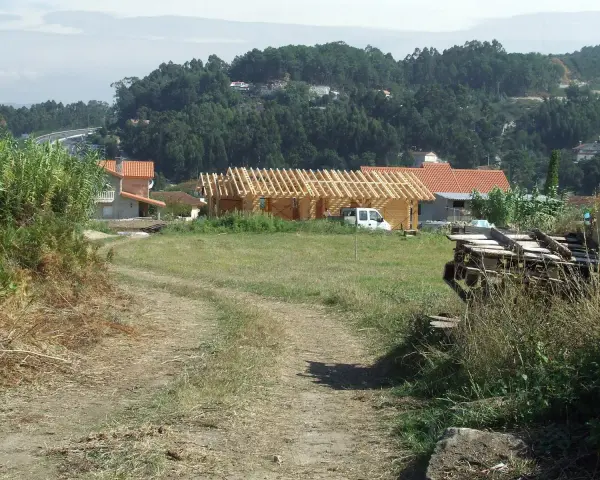 Terreno rural con construcción de madera, casas y vegetación. Se observa un camino de tierra y una posible servidumbre de acueducto en el paisaje.