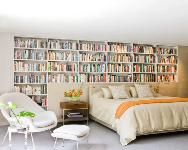 Dormitorio con una pared entera de estanterías llenas de libros, creando un ambiente acogedor en estas casas con biblioteca.
