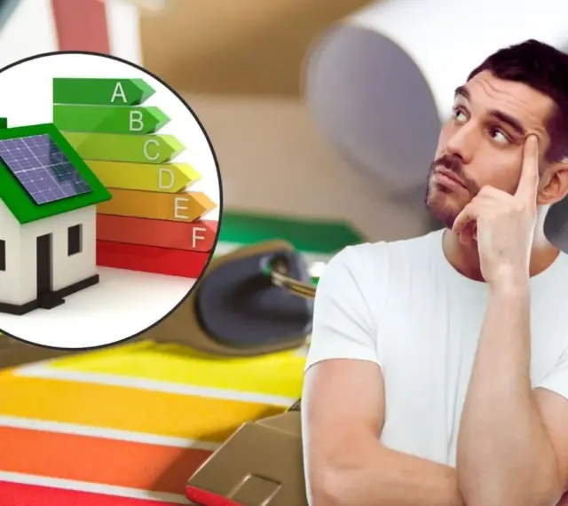 Hombre pensativo junto a una casa con paneles solares y escala de eficiencia energética, pensando en contratos de alquiler.