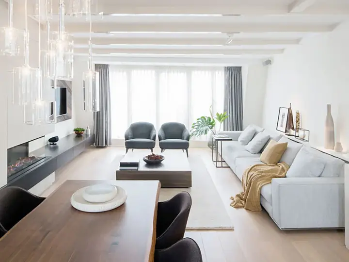 Elegante salón comedor dos ambientes con chimenea, sofás grises, mesa de centro y comedor de madera.