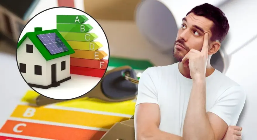 Hombre pensativo junto a una casa con paneles solares y escala de eficiencia energética, pensando en contratos de alquiler.