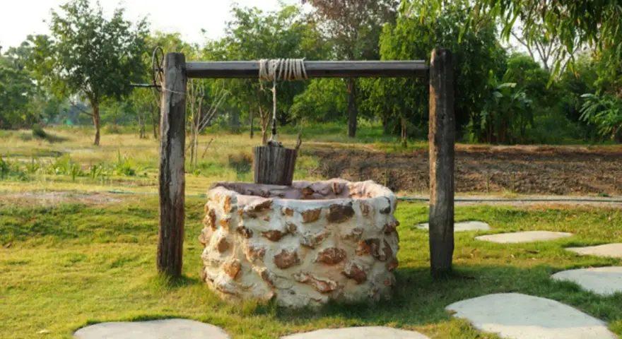 Pozo de piedra con cubo de madera colgando. Interesado en cuanto cuesta hacer un pozo así.