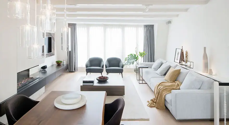 Elegante salón comedor dos ambientes con chimenea, sofás grises, mesa de centro y comedor de madera.