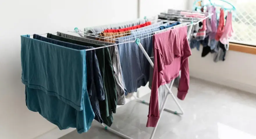 Tendedero desplegado con ropa de varios colores, una solución práctica para tender la ropa en un piso sin terraza.