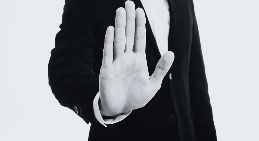 Mano extendida en señal de alto, con un traje oscuro. Representa el derecho de reversión, un límite claro.