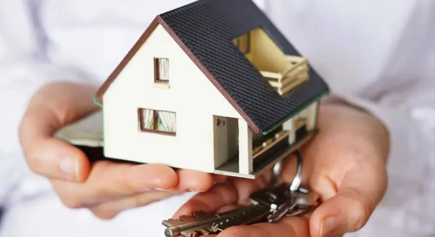Manos sostienen una maqueta de casa y llaves. ¿Puedo vender mi casa sin consentimiento de mis hijos?