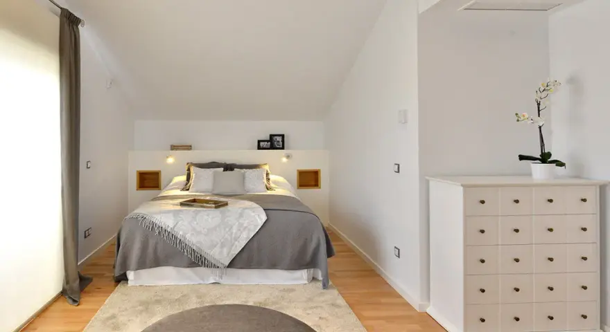 Habitación hermanos poco espacio, con cama doble, alfombra y cómoda blanca.