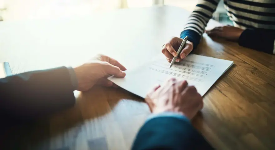 Manos firmando un contrato de alquiler de piso. Los padres avalan el alquiler.