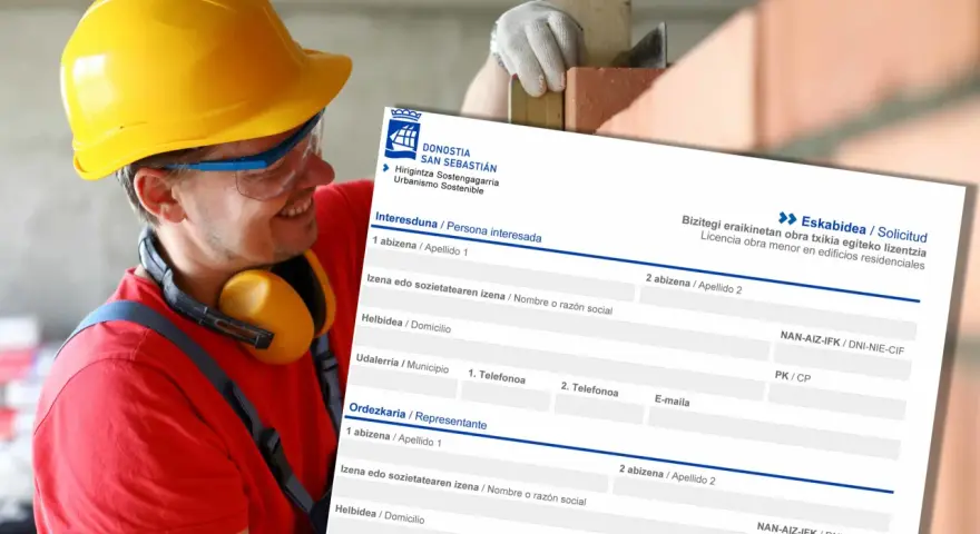 Obrero con casco amarillo sonríe mientras revisa un formulario de solicitud de licencia de obra menor en edificios residenciales.