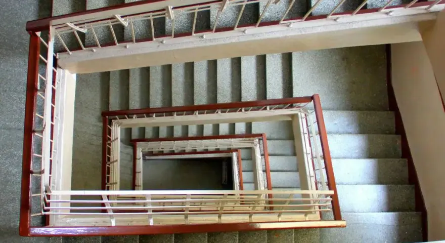 Vista cenital de un **rellano edificio** con escaleras en espiral, barandillas de metal y hormigón.