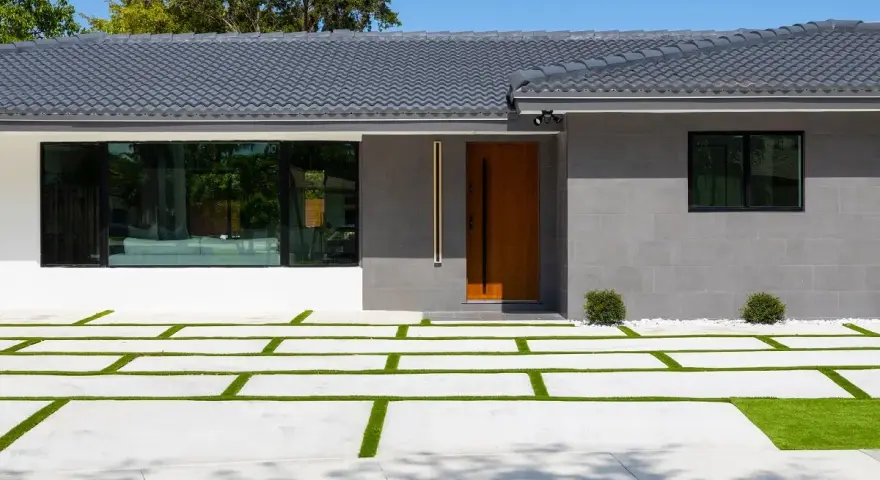 Casa moderna con entrada de madera y ventanal. El camino de acceso combina cemento y césped, ideal si me separo y quiero quedarme el piso.