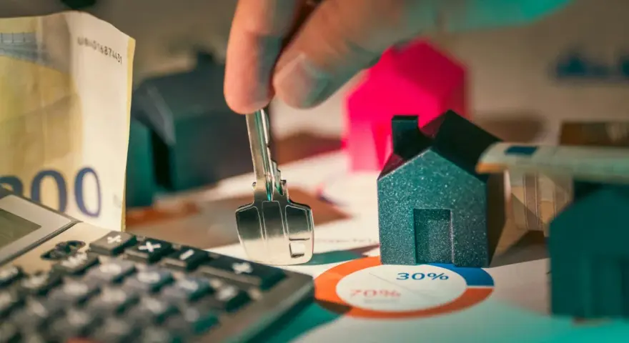 Llaves, dinero y casas en miniatura sobre un gráfico. ¿Es posible empadronarse sin contrato de alquiler?