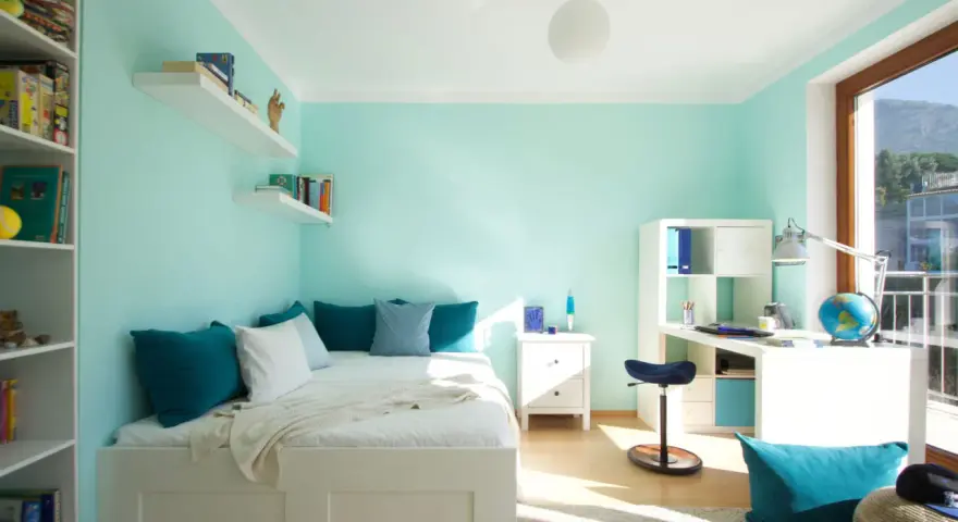 Habitación con pared verde menta y gris, cama blanca, estanterías y escritorio.