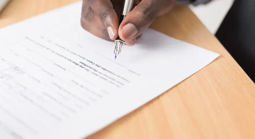 Mano firmando un documento legal. Se puede escriturar una casa a nombre de otra persona mediante este tipo de acuerdos.
