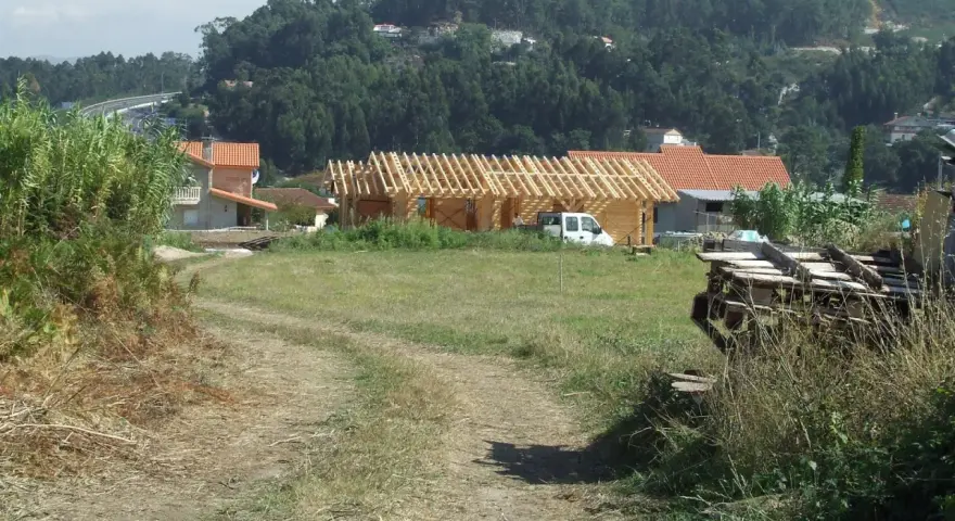 Terreno rural con construcción de madera, casas y vegetación. Se observa un camino de tierra y una posible servidumbre de acueducto en el paisaje.