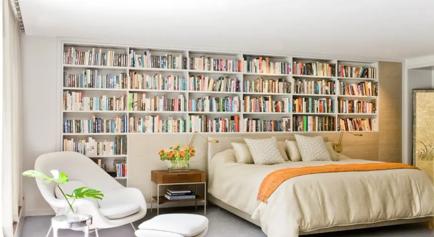 Dormitorio con una pared entera de estanterías llenas de libros, creando un ambiente acogedor en estas casas con biblioteca.