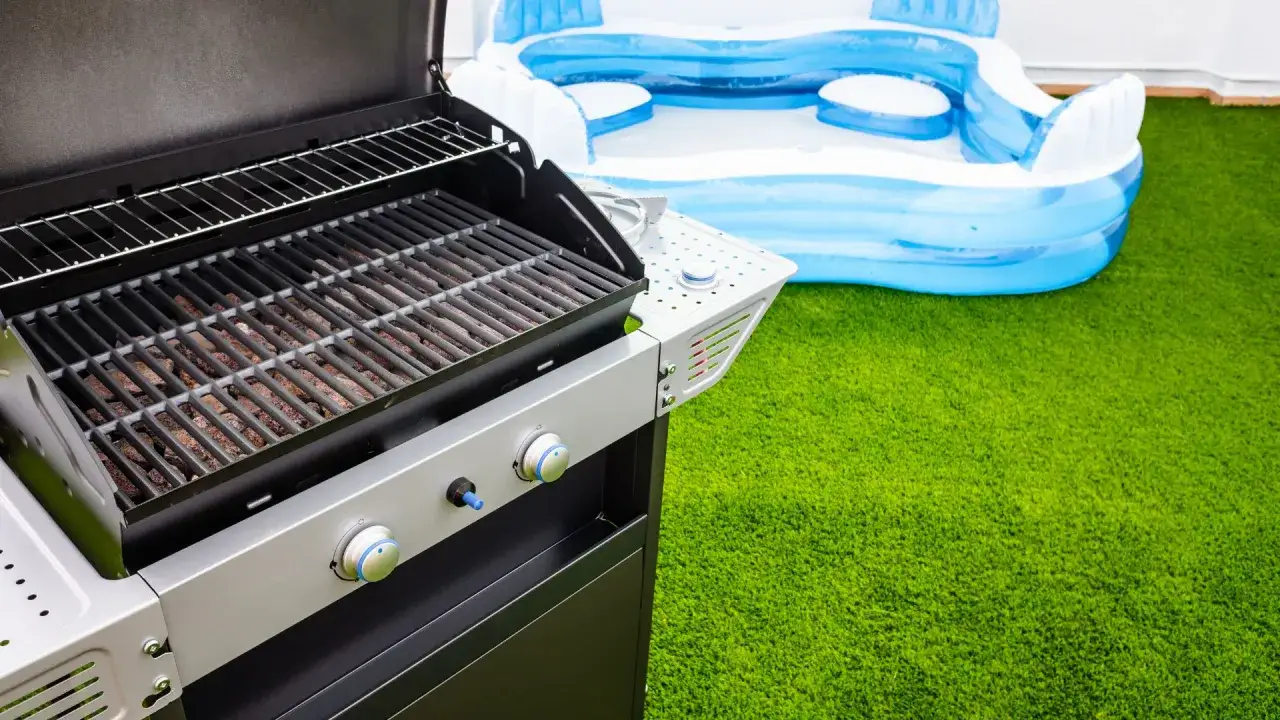 Barbacoa lista para usar en el jard&iacute;n de un chalet, junto a una piscina inflable. Cumpliendo la normativa barbacoas en chalets.