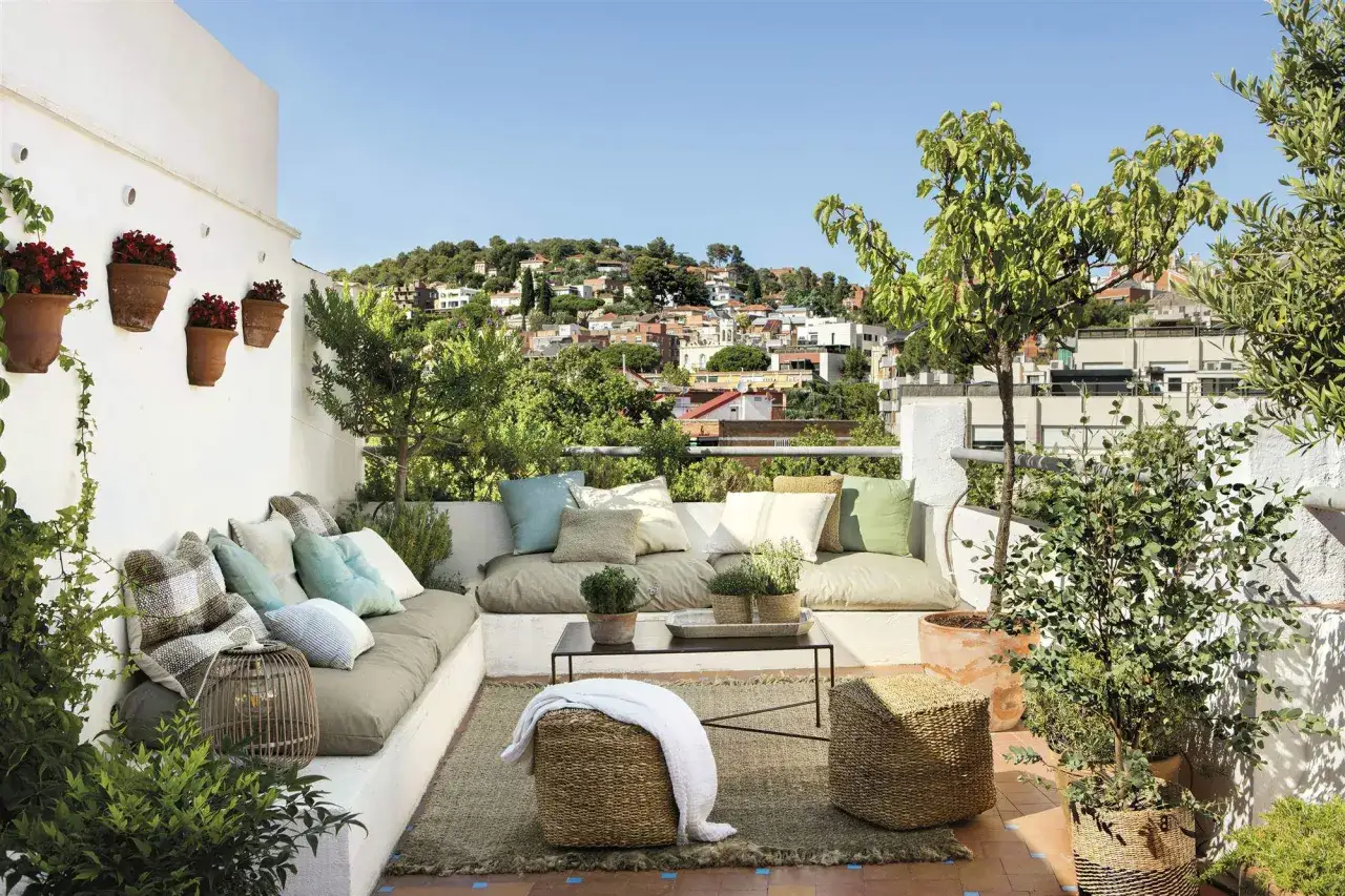 Acogedora decoracion terrazas aticos con encanto, con sof&aacute;s, cojines, plantas y vistas a la ciudad.
