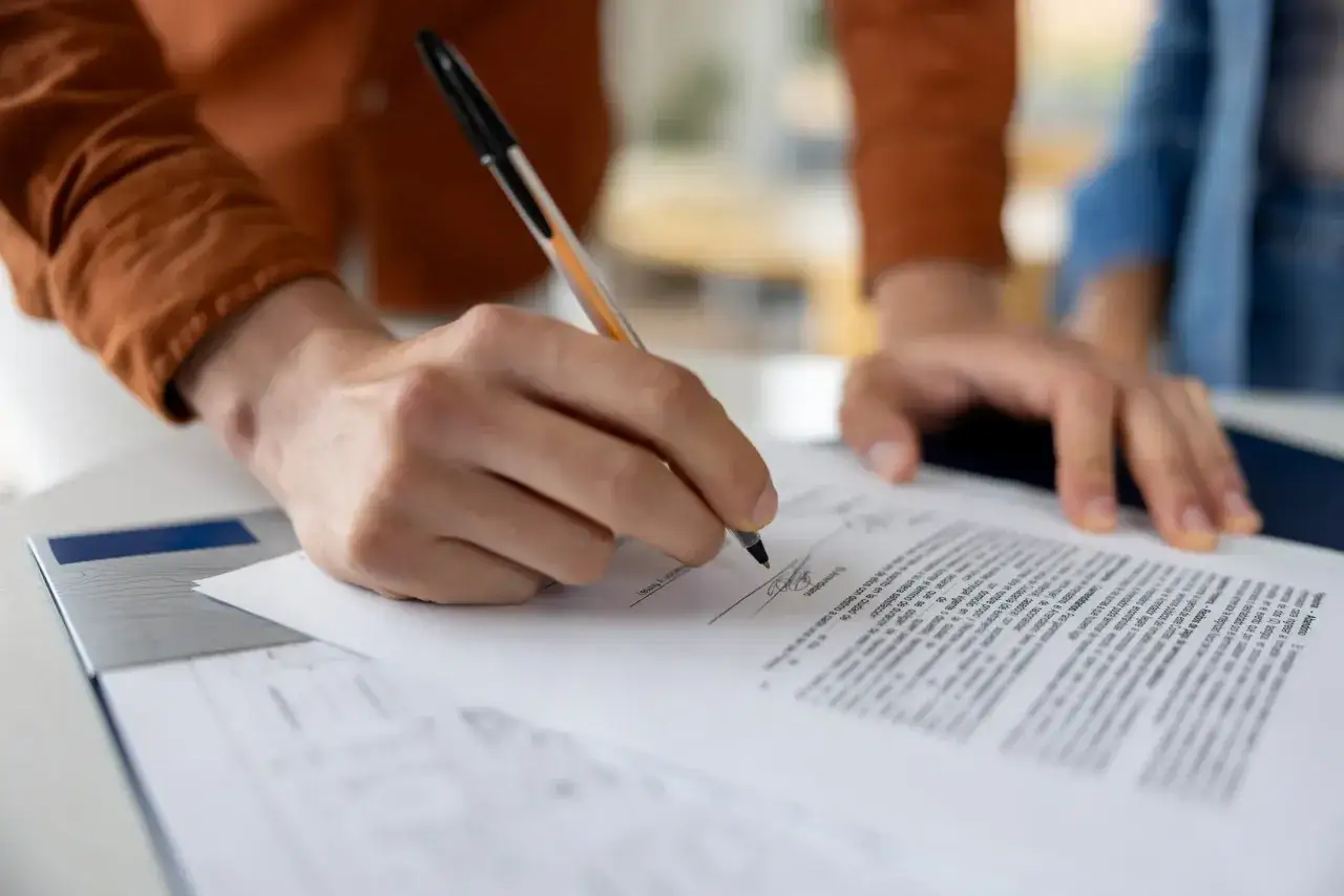 Firma de contrato para comprar casa sin escrituras. Manos firmando un documento legal.