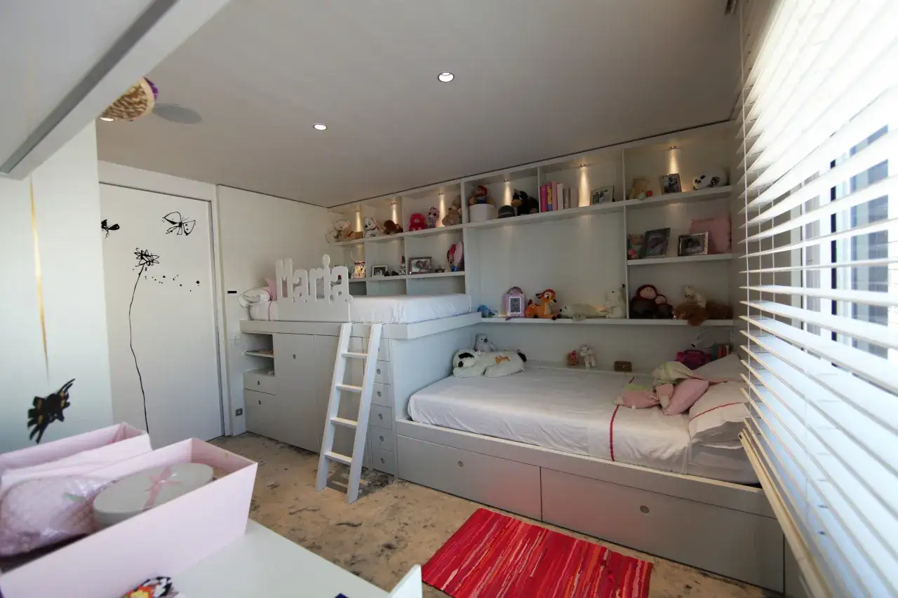Habitaci&oacute;n hermanos poco espacio con literas, estanter&iacute;as llenas de peluches y un nombre 