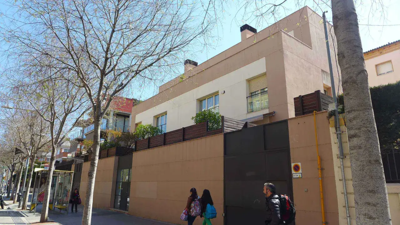 Edificio moderno en Barcelona, listo para su inspecci&oacute;n t&eacute;cnica. Fachada beige y marr&oacute;n, con rejas y &aacute;rboles.