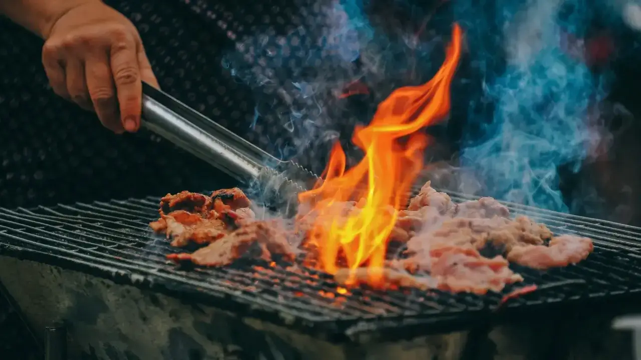 Carne a la parrilla con llamas intensas y humo azul. &iexcl;Cuidado con las multas por hacer barbacoas en terrazas!