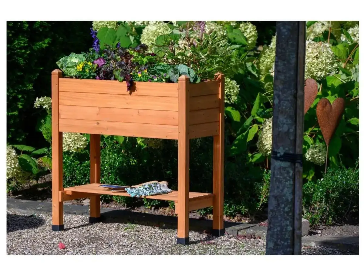 Macetero elevado de madera con diversas plantas, ideal para mostrar qu&eacute; se puede plantar ahora. Incluye guantes de jardiner&iacute;a en la repisa inferior.