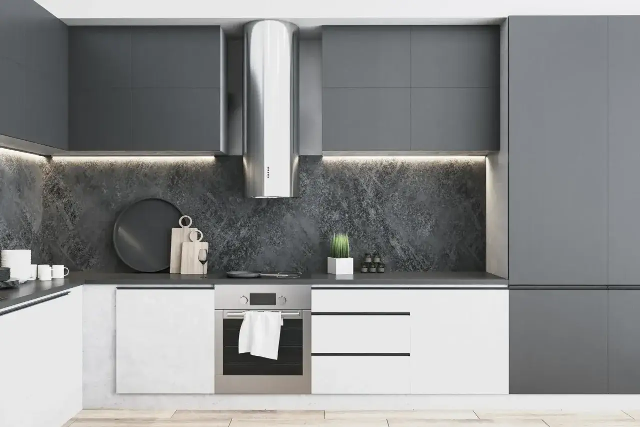 Cocina blanca y gris oscuro con campana extractora de acero inoxidable, encimera de piedra oscura y armarios modernos.