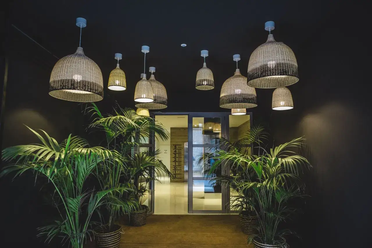 Ideas para como decorar un portal de vecinos: l&aacute;mparas de mimbre y plantas verdes crean un ambiente acogedor y natural.