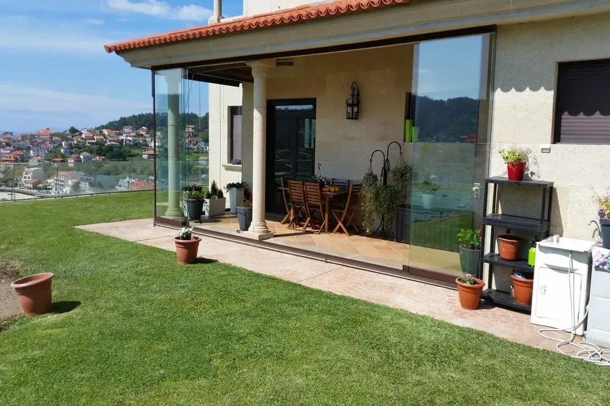 Un porche acristalado con vistas a un pueblo. Ideal para saber como cerrar un porche y disfrutar del exterior todo el a&ntilde;o.