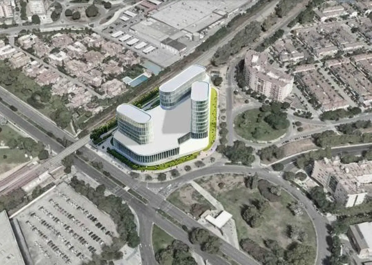 Vista a&eacute;rea de un moderno edificio de oficinas con fachadas curvas, rodeado de zonas verdes y urbanizaciones. El suelo terciario se integra con v&iacute;as de comunicaci&oacute;n y aparcamientos.