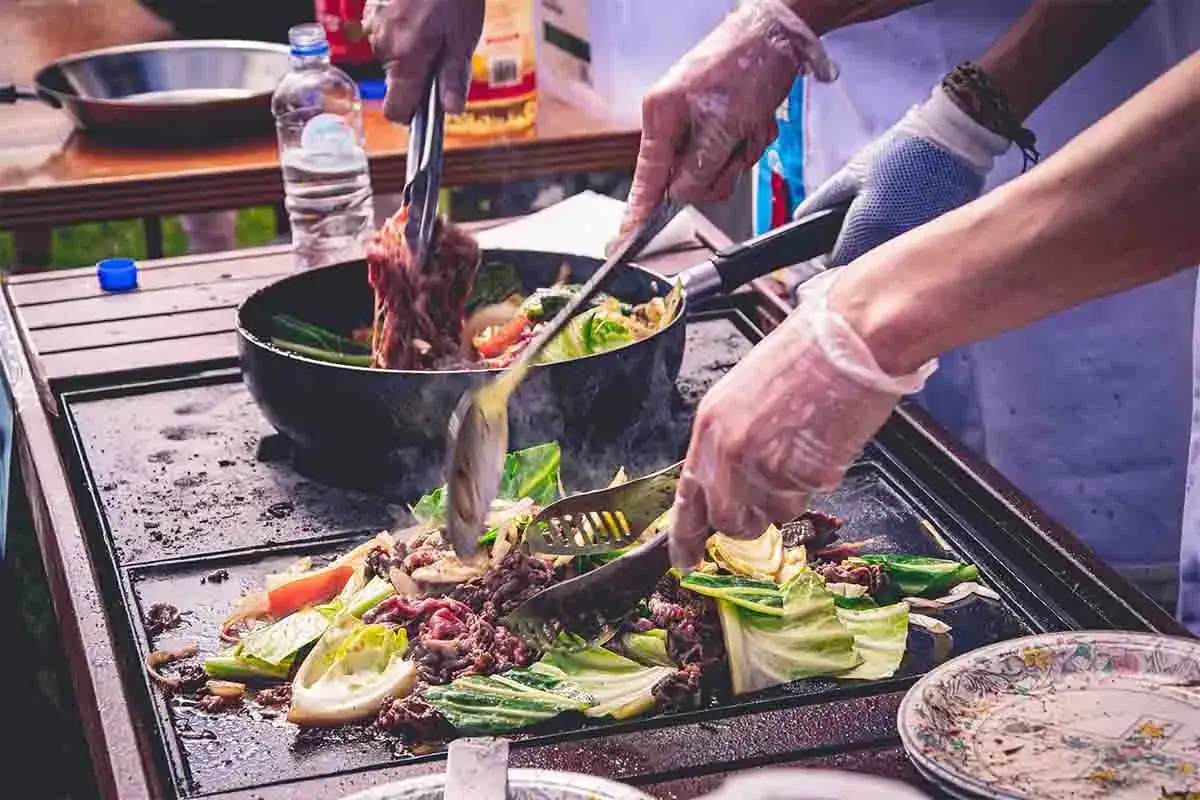 Cocina al aire libre, carne y verduras en plancha. Cumpliendo la normativa barbacoas Catalunya para disfrutar de la comida.