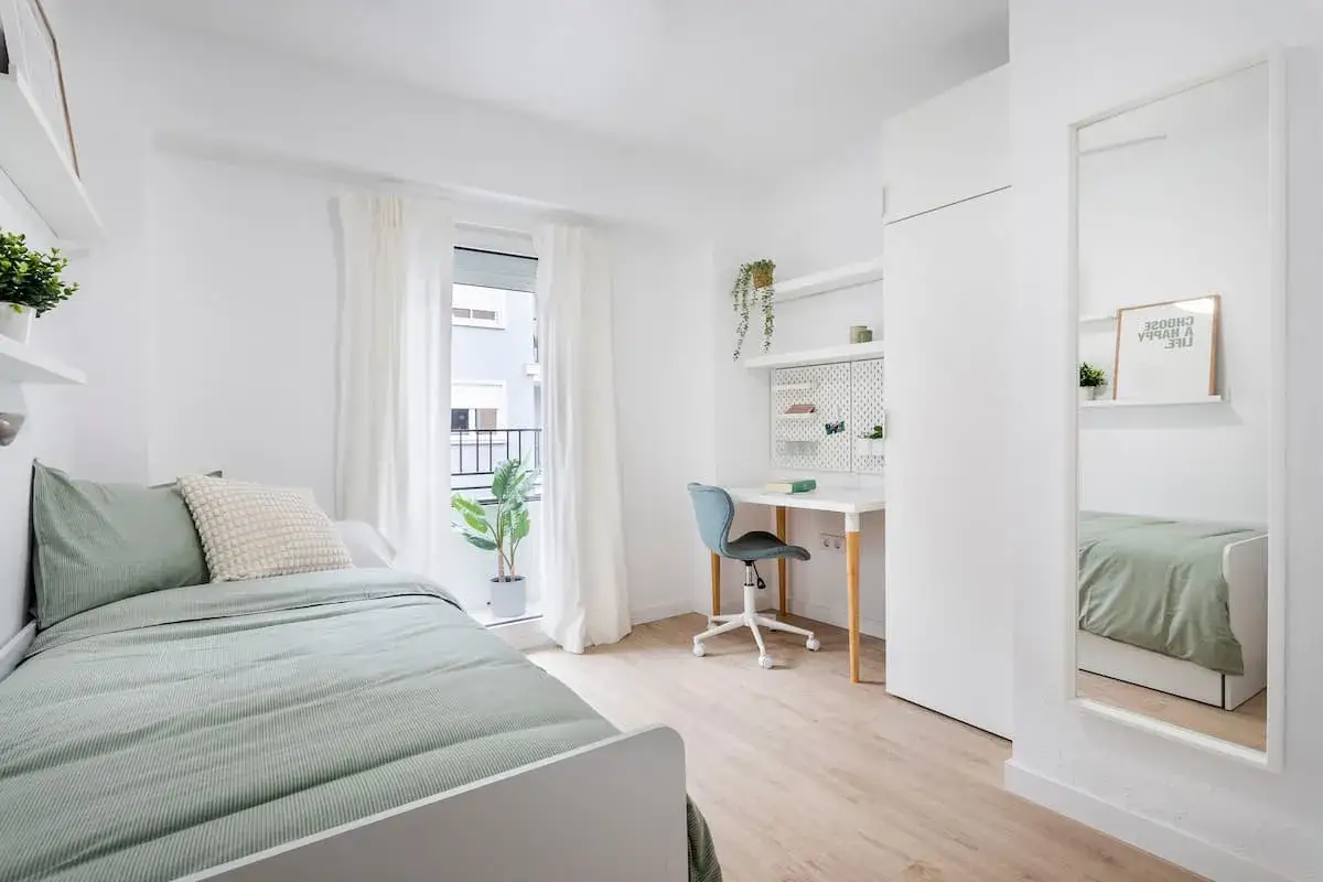 Habitaci&oacute;n luminosa con cama, escritorio y espejo. Ideal para decorar piso de alquiler low cost con estilo y funcionalidad.