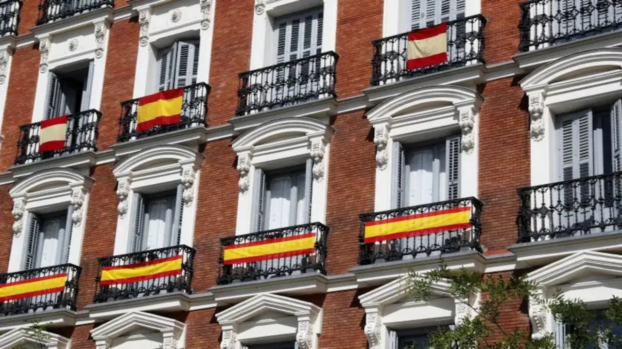 Varias banderas espa&ntilde;olas ondean en los balcones de un edificio de ladrillo rojo. &iexcl;Qu&eacute; orgullo poder poner una bandera en mi casa!