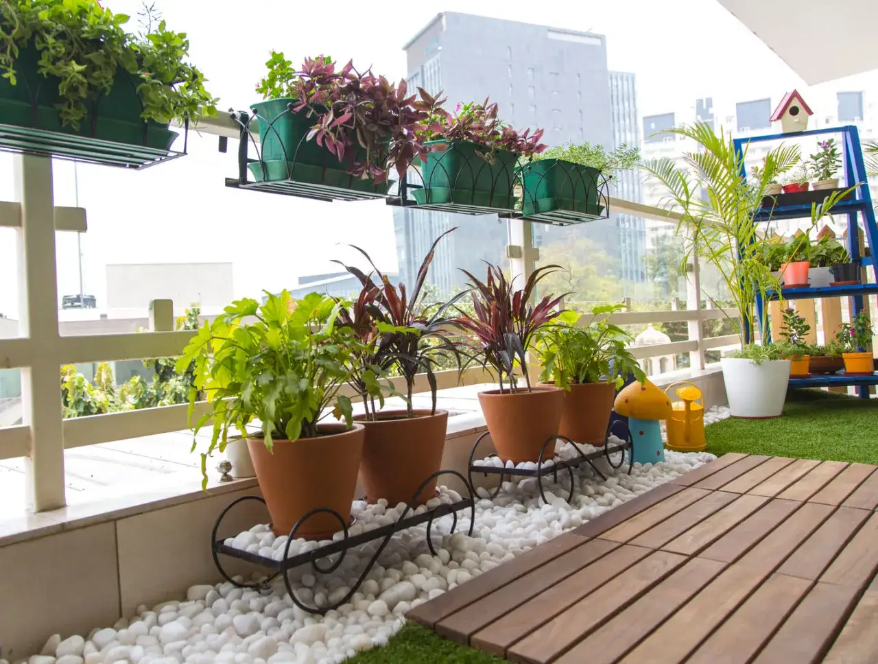Ideas para decorar terrazas barato: plantas en macetas de terracota y estanter&iacute;as azules con vegetaci&oacute;n crean un oasis urbano.