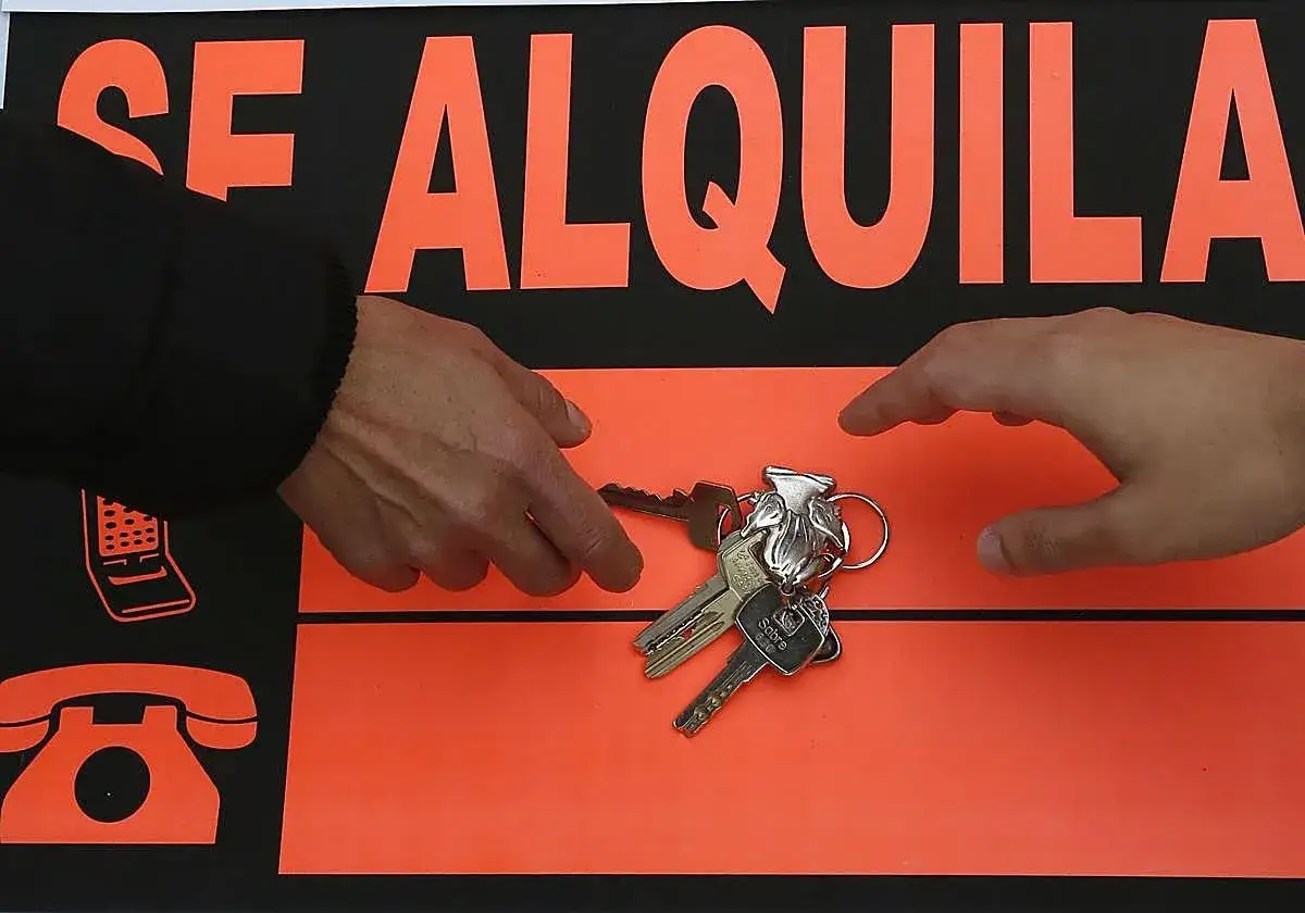 Manos intercambian llaves frente a un cartel 