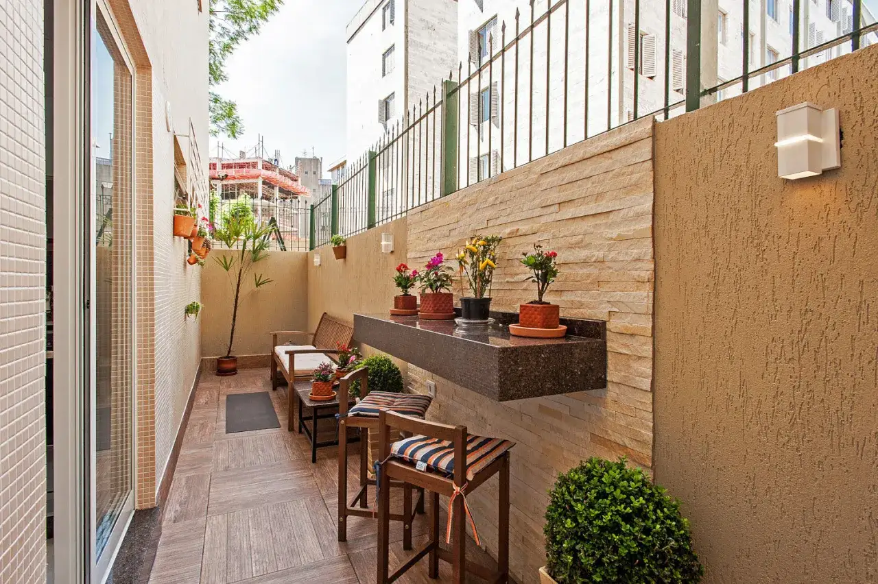 Un balc&oacute;n acogedor con muebles de madera, plantas y un estante flotante, ideal para disfrutar de peque&ntilde;os patios.