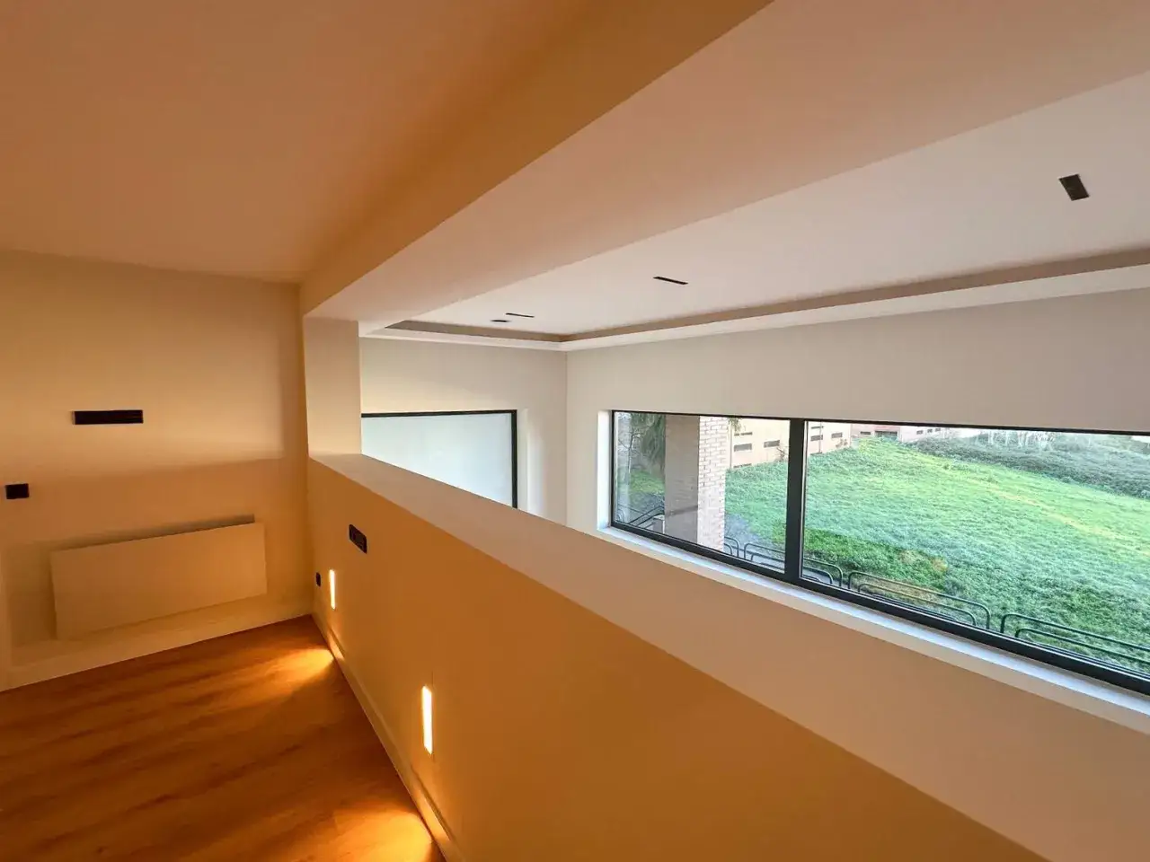 Interior moderno con suelo de madera y gran ventanal. Cumple los requisitos para convertir un local en vivienda.