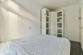 Un armario blanco con puertas de cristal es una solución ideal para saber donde colocar el armario en un dormitorio pequeño, maximizando el espacio.