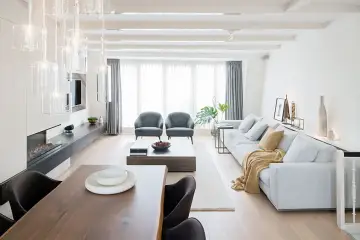 Elegante salón comedor dos ambientes con chimenea, sofás grises, mesa de centro y comedor de madera.