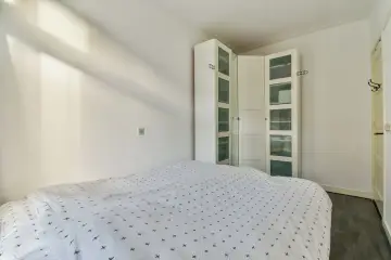 Un armario blanco con puertas de cristal es una solución ideal para saber donde colocar el armario en un dormitorio pequeño, maximizando el espacio.